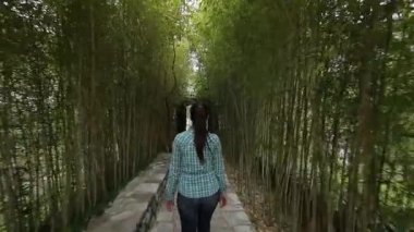 Kız bir bambu koru üzerinde yürür. İzleme çerçeve arkasında
