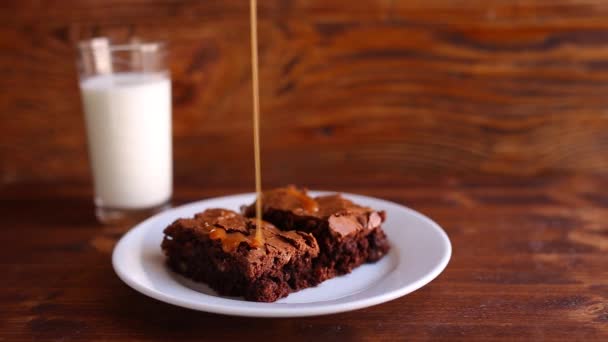 Brownie en un plato, en una textura de madera. Coche salado dulce regado — Vídeo de stock