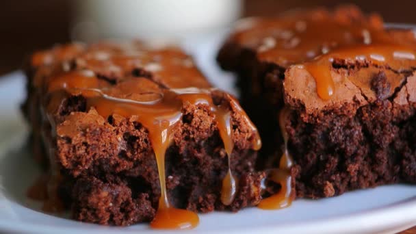 Brownie en un plato, en una textura de madera. Coche salado dulce regado — Vídeo de stock