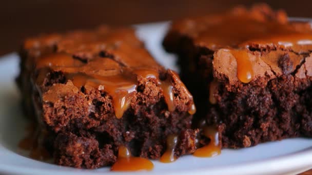 Brownie em um prato, em uma textura de madeira. Carro salgado doce de água — Vídeo de Stock