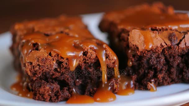 Brownie en un plato, en una textura de madera. Coche salado dulce regado — Vídeos de Stock