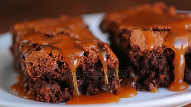 Brownie em um prato, em uma textura de madeira. Carro salgado doce de água — Vídeo de Stock