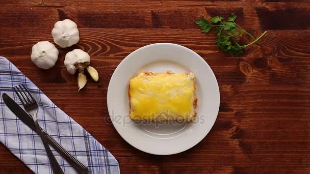 Rechteckige Lasagne auf einem weißen Teller. auf einem hölzernen Hintergrund — Stockvideo