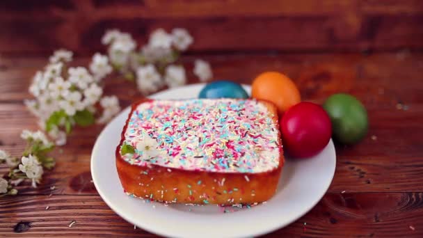 Easter cake on a plate, on a wooden board. The painted eggs in d — Stock Video