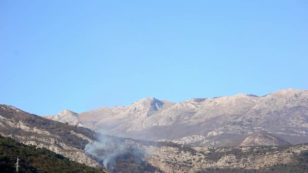 Oheň v horách v odpoledních hodinách. Kouř nad horami — Stock video