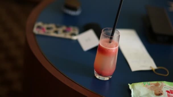 Roter Cocktail im Glas mit Strohhalm auf dem Tisch — Stockvideo