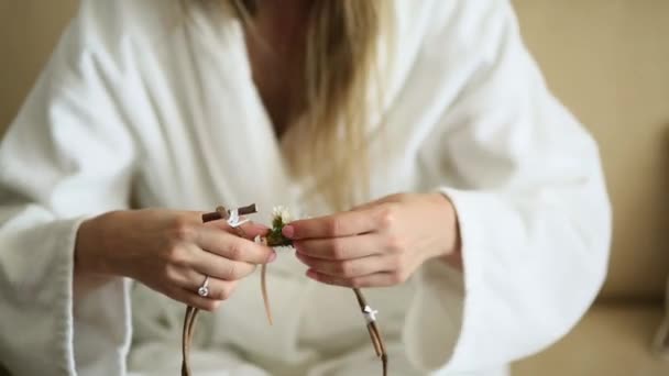 La novia en un vestido de hotel blanco tejió guirnalda gypsophila — Vídeos de Stock