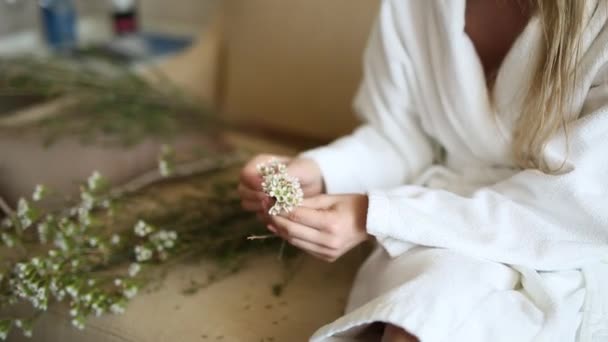 La mariée dans une robe d'hôtel blanche tisser couronne gypsophila — Video