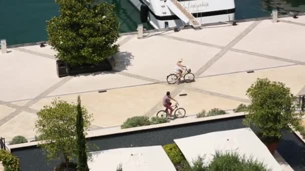 Cyclists ride bicycles by the marina for yachts. District for th — Stock Video