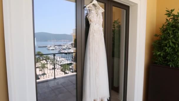 Vestido de novia El vestido de novia cuelga en la ventana, en la que th — Vídeos de Stock