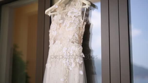 Свадебное платье невесты висит на окне, в котором й — стоковое видео