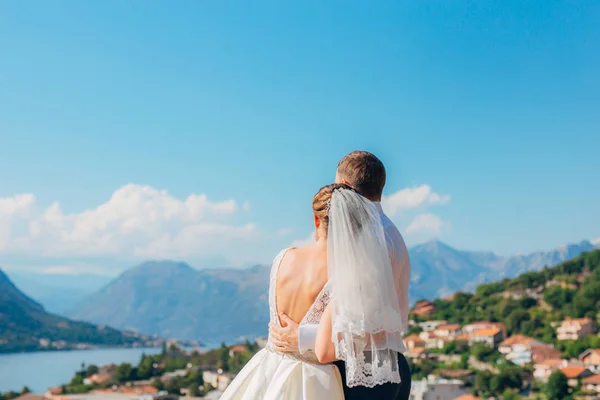 Os recém-casados abraçam e olham para Kotor Bay em Montenegro — Fotografia de Stock