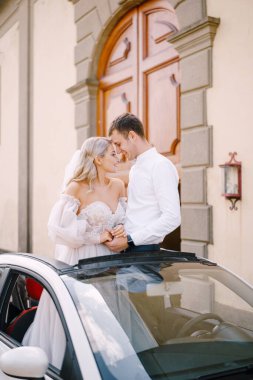 Güzel gelin ve damat ayağa kalktı ve Lilliano Şarap, Toskana, İtalya 'nın Medici Villasının önünde üstü açık bir arabada alnına yaslandı..