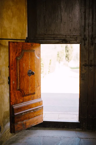 Old wooden door open at the Medici Villa of Lilliano Wine Estate, Tuscany, Italy.