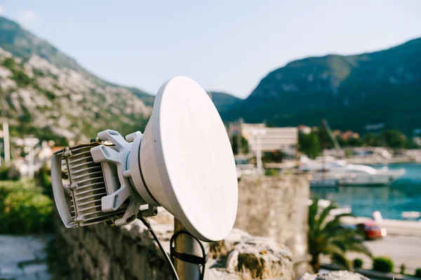 Antenne wi-fi extérieure dans la ville. Communication 3G et 4G. Couverture de l'opérateur mobile. Une antenne blanche sur un poteau sur le mur de la vieille ville de Kotor au Monténégro . — Photo