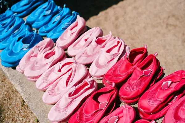Sepatu Renang. Banyak pasangan sepatu untuk mandi merah, merah muda dan biru warna terletak di pantai — Stok Foto