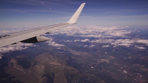 Blick aus dem Flugzeug auf den Gran Sasso und den Nationalpark Monti della Laga in Italien. Luftaufnahme von schönen weißen Haufenwolken am blauen Himmel. Tragfläche eines Flugzeugs aus einem Bullauge. Reisekonzept — Stockvideo