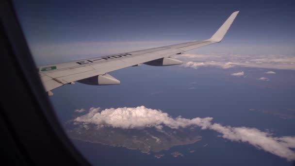 Pohled z letadla na ostrov Vis v Chorvatsku. Letecký pohled na krásné bílé haldy mraků na modré obloze. Křídlo letadla z okénka. Cestovní koncept — Stock video