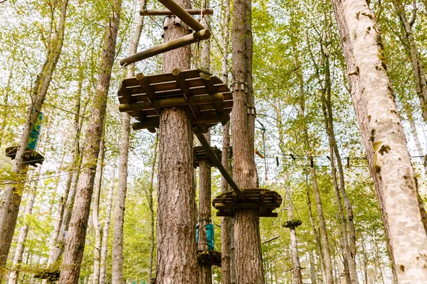 Park wspinaczkowy wysoko na drzewach. Bieg przeszkód w wesołym miasteczku. Zajęcia sportowe na świeżym powietrzu. Wyzwanie przygoda sport solowy. Element wysokich lin w lesie. — Zdjęcie stockowe