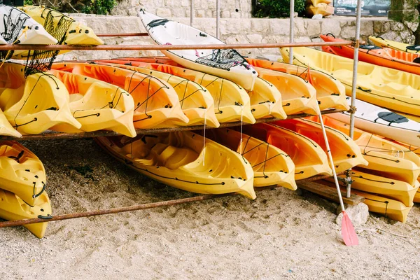 A warehouse of yellow kayaks on the shore. Single kayaks. Rental kayakshop store on sandy beach