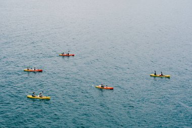 Bir grup turist, Hırvatistan 'ın eski Dubrovnik kenti yakınlarındaki deniz kanolarında çift halinde seyahat ediyor. Bayrak seyahati kavramı. Havadan üst görünüm.