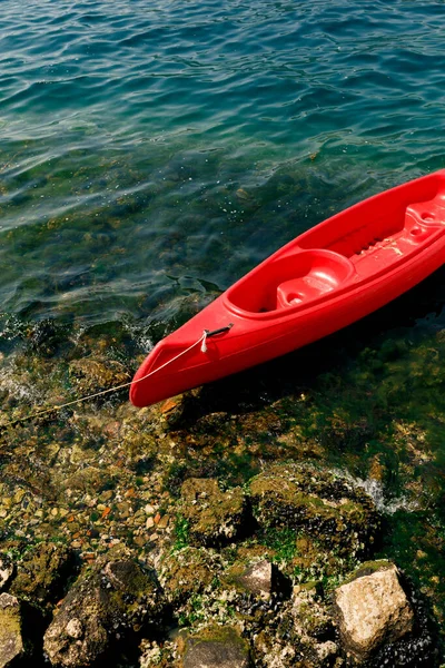 Cerca de kayak rojo amarrado cerca de la orilla. Playa rocosa del mar Adriático en Montenegro . — Foto de Stock