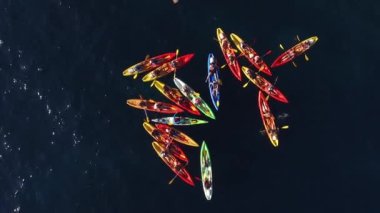 Bir grup kanocu kanolarını denizde bir yığın halinde topladı. Grup halinde çift halinde yüzün. Bayrak seyahati kavramı. Havadan üst görünüm.
