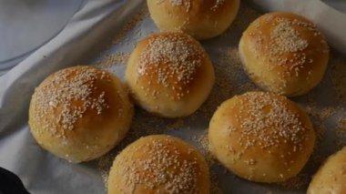 Hamburgerler fırından yeni çıktı, hala sıcak, susam tohumları bol bol serpiştirilmiş. Ev yapımı yuvarlak domuz çörekleri, kırmızı kabuklu.