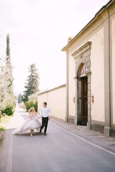 Hermosos novios corriendo de la mano fuera de la antigua villa en Italia, en Toscana, cerca de Florencia . —  Fotos de Stock