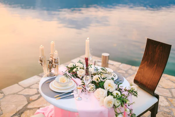 Close-up van een bruiloft eettafel bij de receptie. Romantisch diner bij zonsondergang op het strand. Een tafel aan zee, bij zonsondergang. Diner voor twee. Romantisch afspraakje — Stockfoto