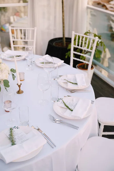 Recepción de mesa de cena de boda. Primer plano de una mesa redonda de boda con platos blancos y un menú encerrado en una servilleta. Los dispositivos se encuentran junto a la placa de acuerdo con los requisitos de etiqueta . — Foto de Stock