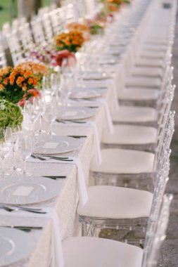 Düğün masası resepsiyonu. Yukardan, beyaz yuvarlak plakalardan yakından bak. Pembe, turuncu, yeşil çiçekler. Pembe güller, küçük turuncu güller. Üst görünüm