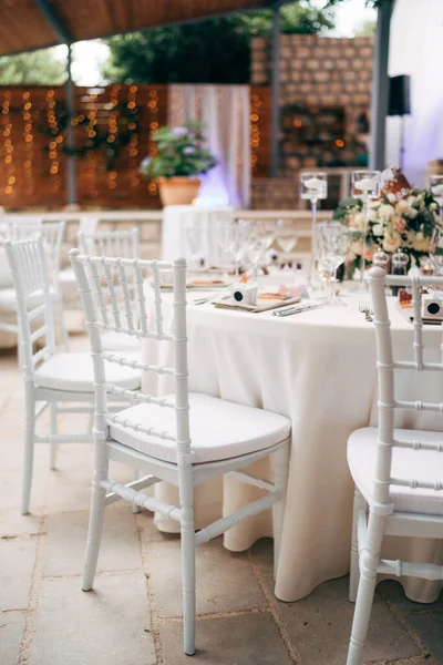 Recepción de mesa de cena de boda. Un primer plano de la silla clásica blanca para la boda de Chiawaris, Tiffany cerca de la mesa redonda, en medio de las luces de la guirnalda — Foto de Stock