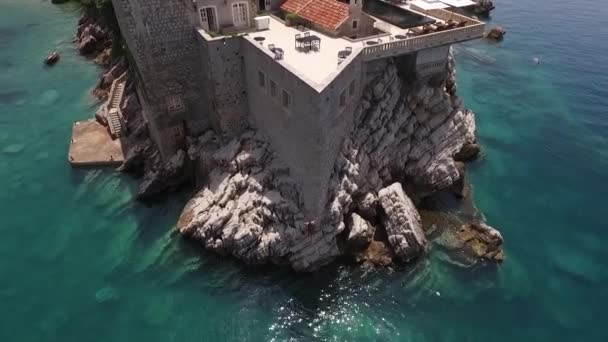 Salto alto en el mar. El tipo salta al agua desde una gran altura desde la pared de la isla de Sveti Stefan en Montenegro . — Vídeos de Stock