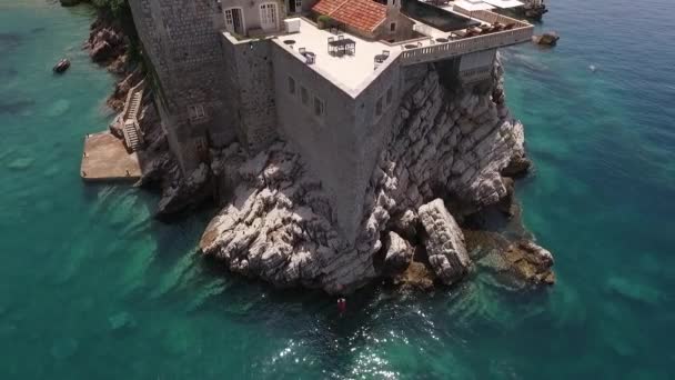 Wysoki skok do morza. Facet wskakuje do wody z dużej wysokości ze ściany wyspy Sveti Stefan w Czarnogórze. spowolnienie — Wideo stockowe