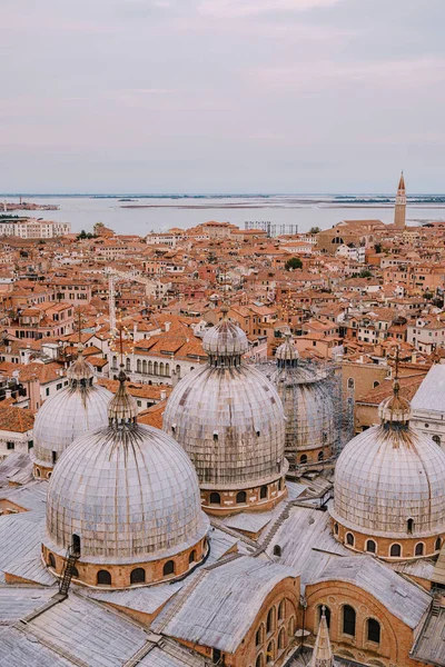 Bovenaanzicht op de St. Marks kathedraal op St. Marks Square, met een grote bakstenen toren. Tegen de achtergrond van betegelde oranje daken van de oude stad Venetië in Italië. — Stockfoto