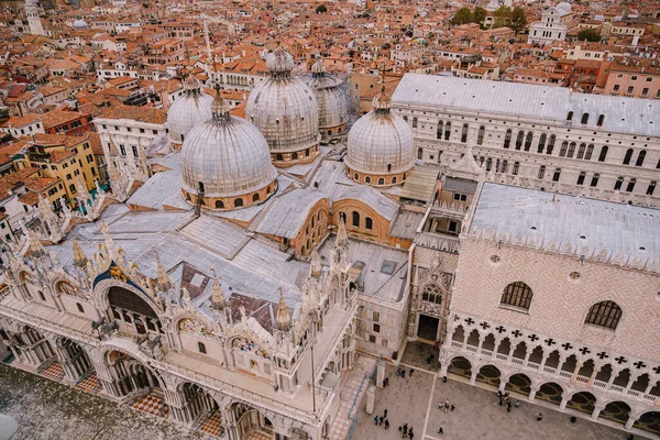 Bovenaanzicht op de St. Marks kathedraal op St. Marks Square, met een grote bakstenen toren. Tegen de achtergrond van betegelde oranje daken van de oude stad Venetië in Italië. — Stockfoto