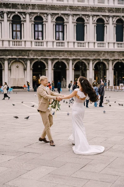 Düğün Venedik, İtalya 'da. Gelin ve damat, San Marco Meydanı 'ndaki güvercinlerin arasında Venedik Ulusal Arkeoloji Müzesi' nin arka planında dans ediyorlar..