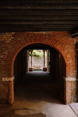 Binadan Venedik, İtalya 'daki evlerin arasındaki dar bir kanala bakın. Tuğla duvarlı bir tünelden manzara, iki antika sütun ve denizde su..