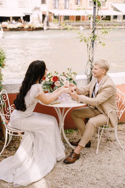A menyasszony és a vőlegény asztaloknál ülnek a Grand Canal partján, és fogják egymás kezét Velencében, Olaszországban. A világ legromantikusabb helye. Egy romantikus vacsorára vár két személyre.. — Stock Fotó
