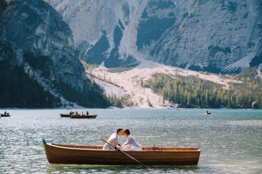 Gelin ve damat İtalya 'daki Lago di Braies' de tahta bir tekneyle denize açılıyorlar. Avrupa 'da düğün, Braies Gölü' nde. Yeni evliler teknede oturup öpüşüyorlar..