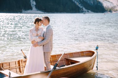 Gelin ve damat, İtalya 'daki Lago di Braies gölünde kürekleriyle ahşap bir teknede yelken açıyorlar. Avrupa 'da düğün - Yeni evliler bir teknede birbirlerine sarılıyorlar.