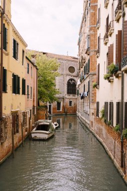 Venedik, İtalya 'da bir kanalın duvarlarına demirlemiş tekneler. Klasik Venedik sokak manzarası - ahşap panjurlar, tuğla evler, köprüler
