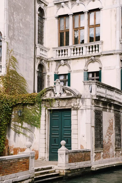 Прекрасний кам'яний арочний вхід до будівлі, зелені двері і класичні венеціанські вікна. Деталі будівельних фасадів на вулицях Венеції (Італія).. — стокове фото