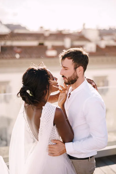 Διαφυλετικό ζευγάρι γάμων. Destination fine-art γάμος στη Φλωρεντία, Ιταλία. Καυκάσιος γαμπρός και Αφροαμερικανή νύφη αγκαλιάζονται σε μια ταράτσα στο ηλιοβασίλεμα. — Φωτογραφία Αρχείου