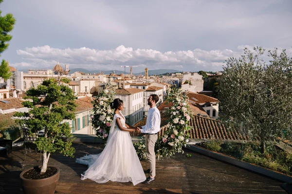 Tujuan pernikahan seni rupa di Florence, Italia. Pasangan pernikahan multietnis. Sebuah upacara pernikahan di atap gedung, dengan pemandangan kota dan Katedral Santa Maria Del Fiore Stok Gambar Bebas Royalti