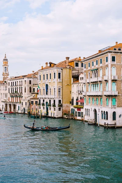 Гондола з туристами пливе вздовж Великого каналу серед фасадів венеціанських домів, що стоять на воді у Венеції (Італія).. — стокове фото