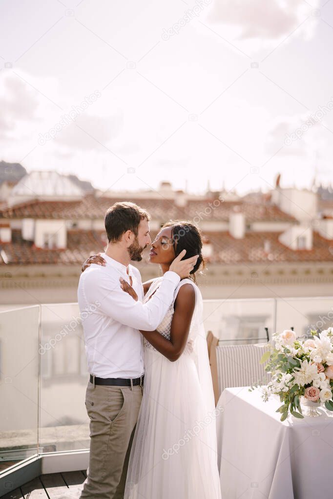 Destination fine-art wedding in Florence, Italy. Mixed-race wedding couple. African-American bride and Caucasian groom stand near the table for a wedding dinner.