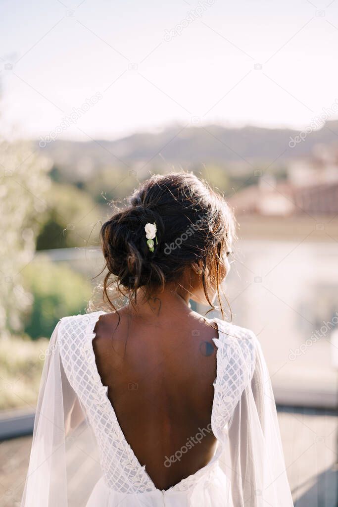Destination graceful wedding in Florence, Italy. An African American bride stands with her back in urban dresses against the backdrop of the cityscape of Florence.