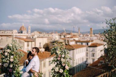 Mixed-race wedding couple. Destination fine-art wedding in Florence, Italy. A wedding ceremony on the roof of the building, with cityscape views of the city and the Cathedral of Santa Maria Del Fiore clipart